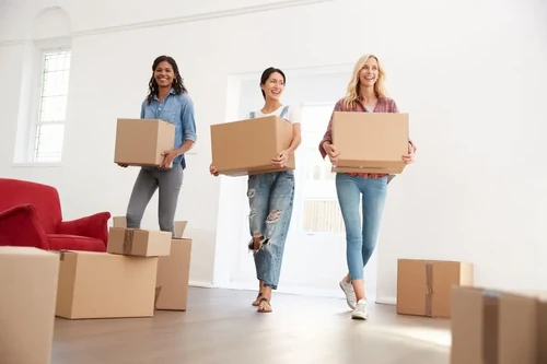 A trio of roommates carry their things into their new home.