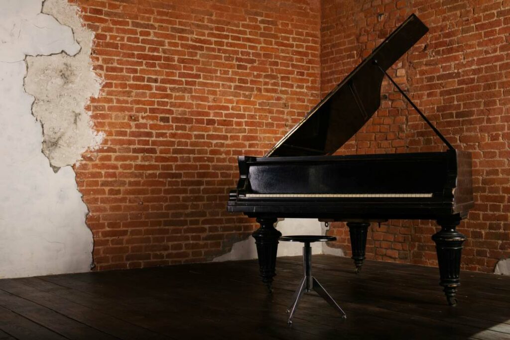 A piano stored in the corner of an old room