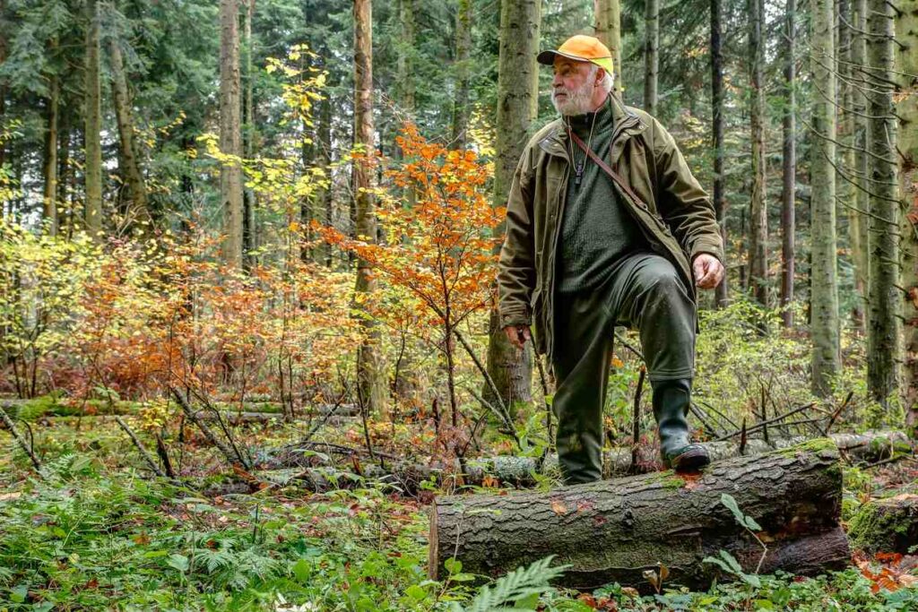 A man stands in the middle of the woods while hunting.