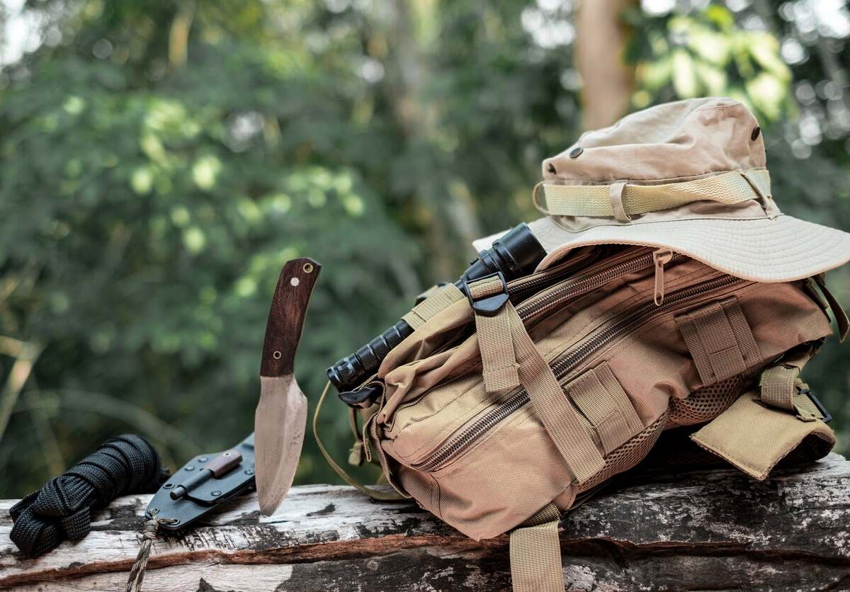 A hunting knife and bag sit on a log during hunting season.